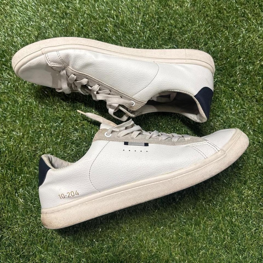 White and navy leather sneakers with a minimalist design, featuring‎ a comfort